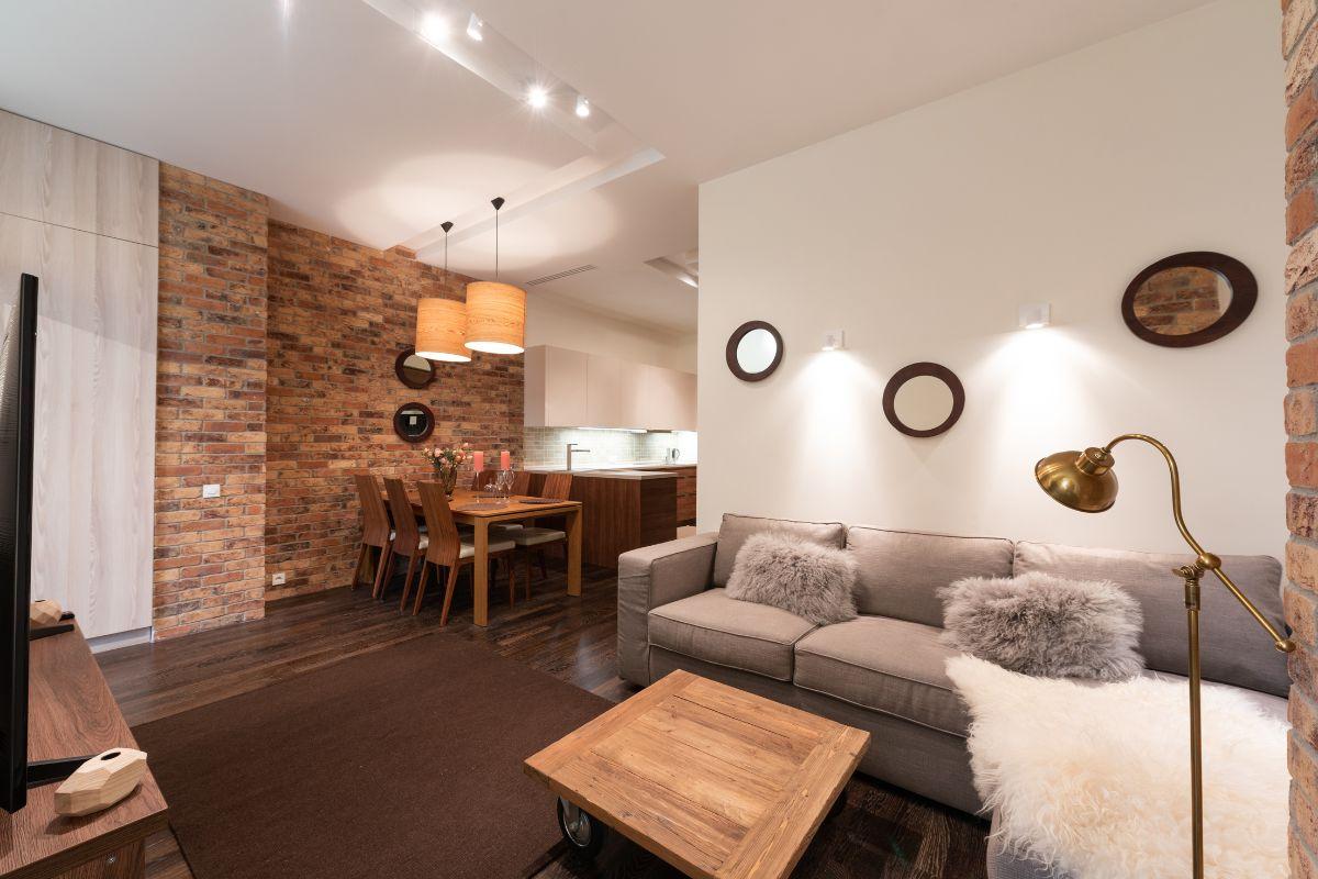 Cozy living and dining area with exposed brick walls, warm lighting, and modern furnishings.