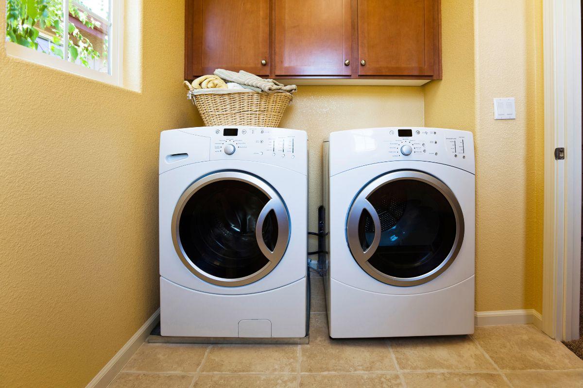 Laundry room with a front-loading washer and dryer, topped with a wicker basket of folded towels.