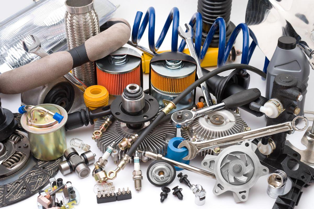 A variety of automotive parts and tools, including filters, springs, spark plugs, and wrenches, arranged on a white surface.