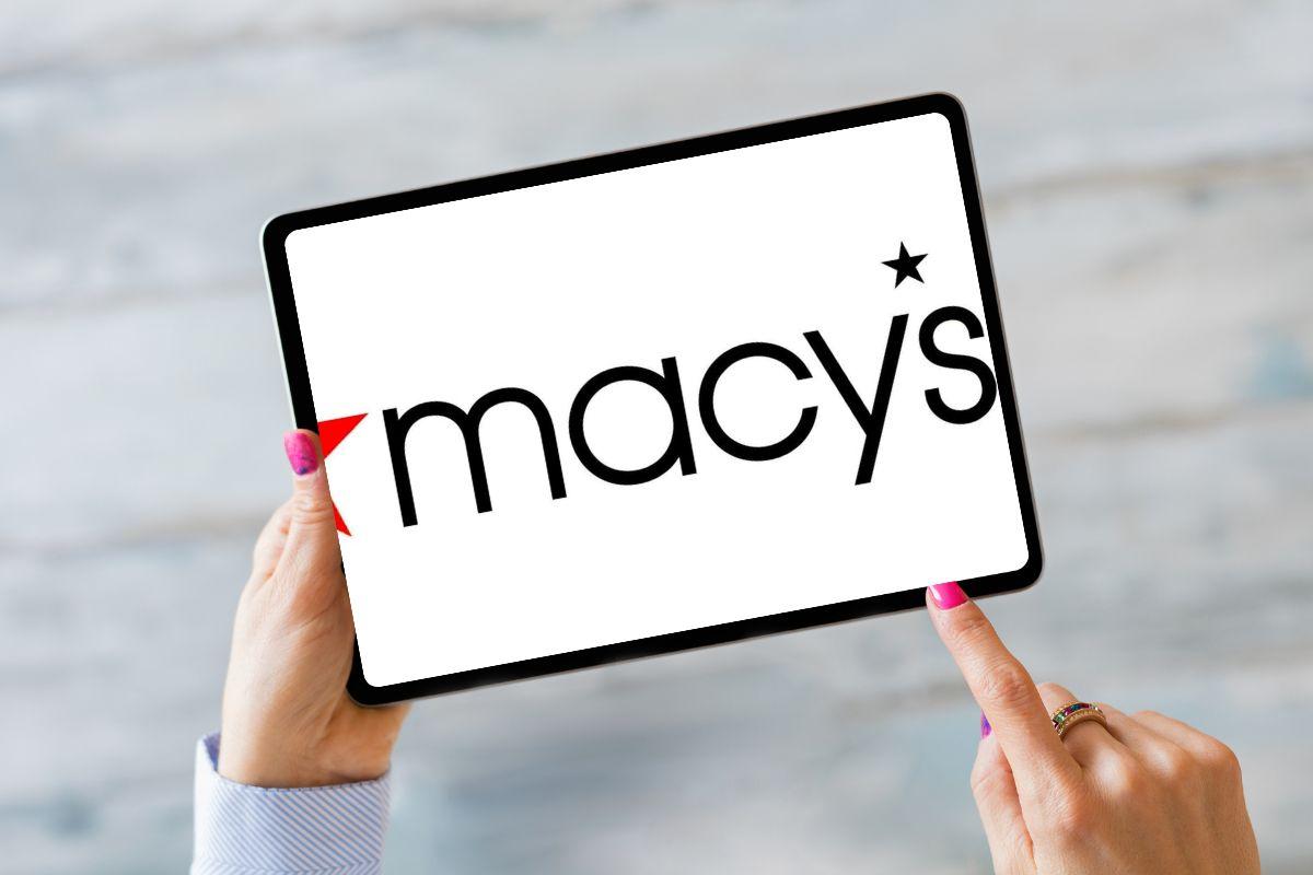 Person holding a tablet displaying the Macy's logo on the screen.