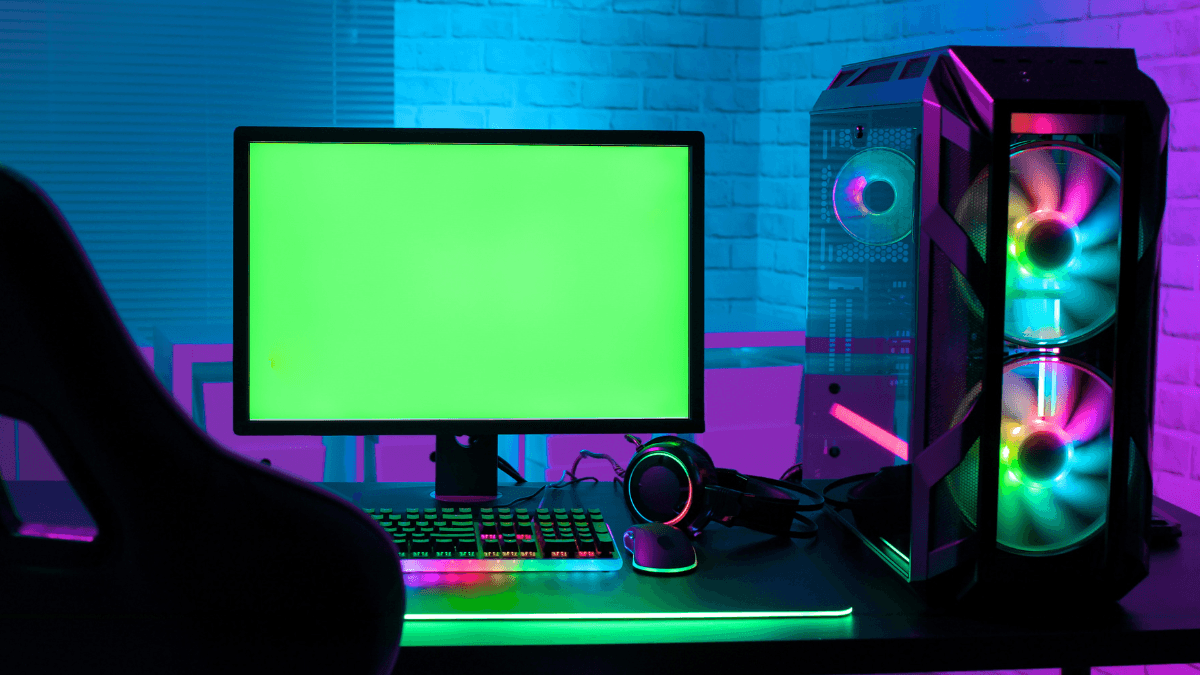 Vibrant gaming setup showcasing a desktop with RGB lighting, a neon-lit keyboard, headphones, and a powerful gaming PC with illuminated cooling fans, set against a modern brick wall.