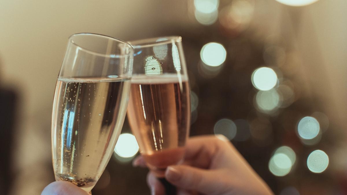 Two people clinking champagne glasses during a celebration, capturing the sparkling detail and festive mood with a warm bokeh background.