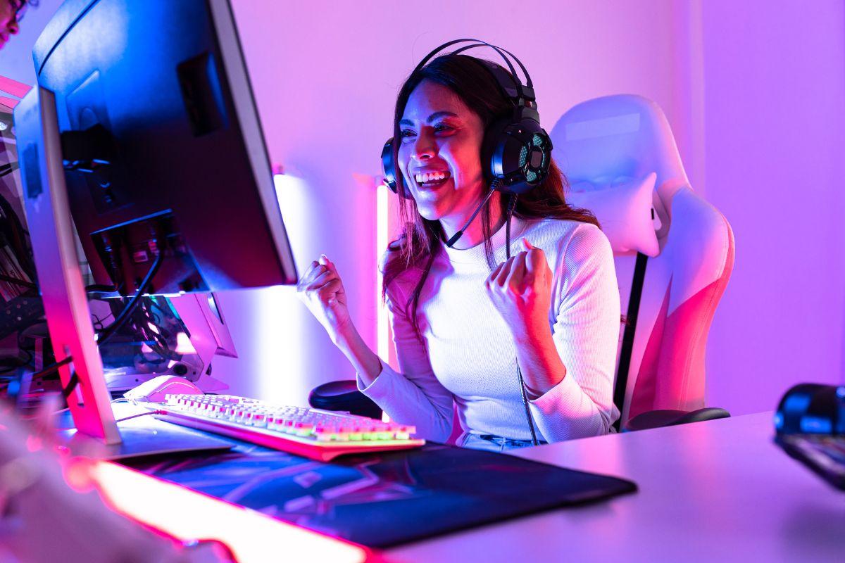 A gamer wearing headphones sits at a dual-monitor setup with colorful LED lighting, fully immersed in a futuristic game environment.