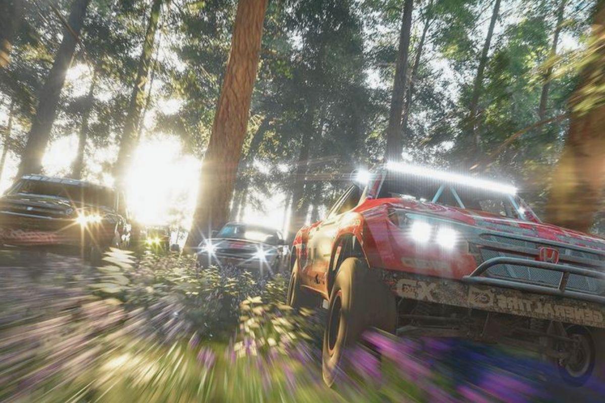 Off-road vehicles race through a dense forest, kicking up dirt and illuminated by sunlight filtering through the trees.