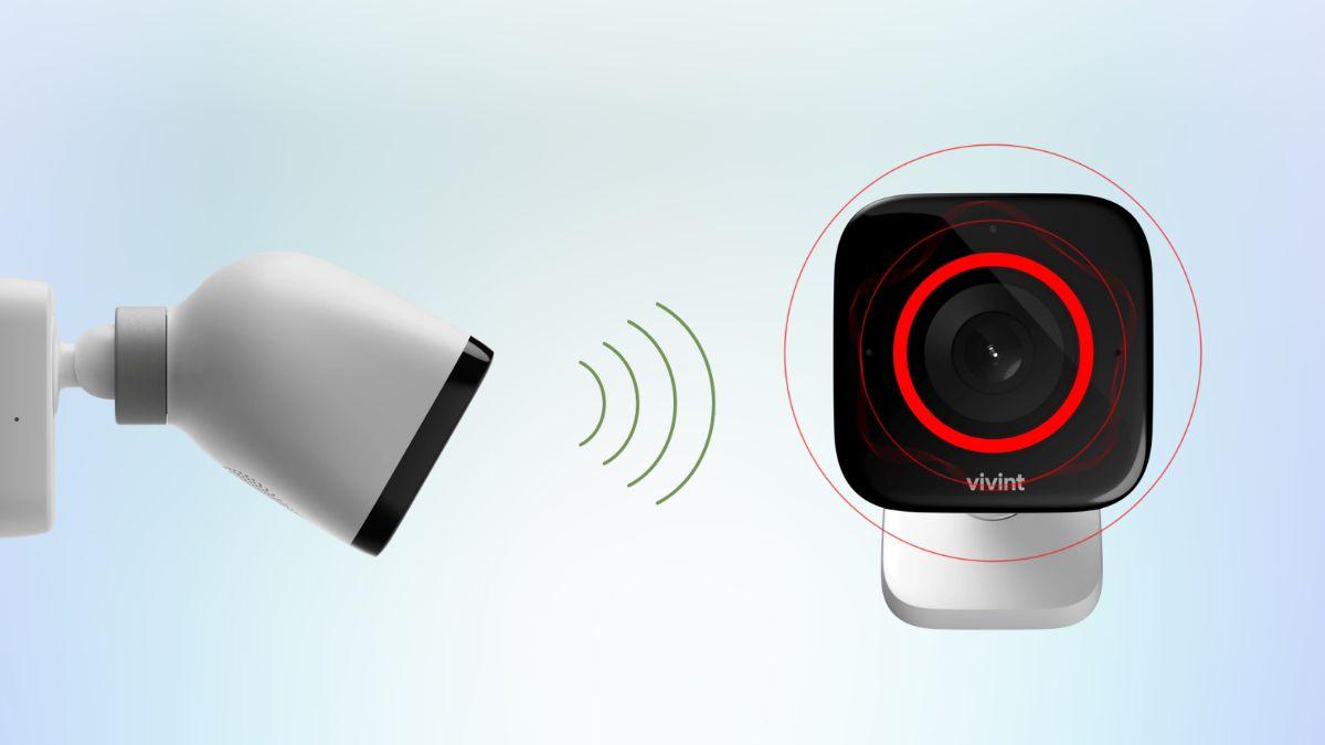 A smart security camera with a red alert ring is detecting a signal from a spotlight camera on the left.
