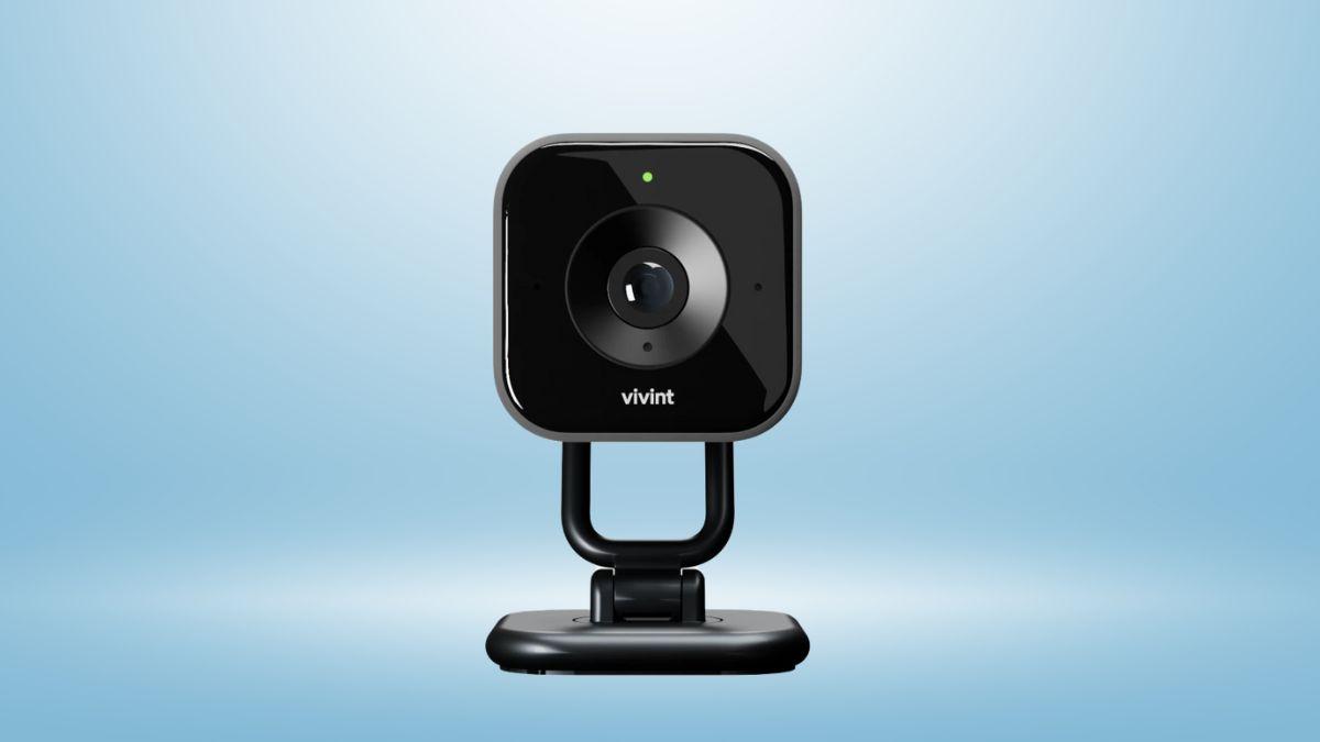A black Vivint indoor security camera with a green indicator light is set against a light blue background.