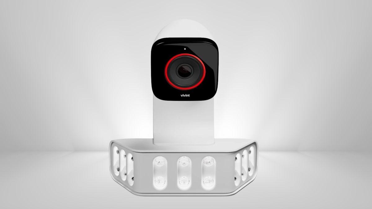 An outdoor security camera with a red alert ring is mounted above a bright LED floodlight.