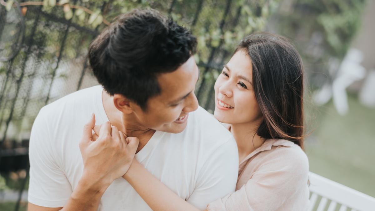 Happy young couple smiling and embracing outdoors, showing affection and connection in a natural setting.