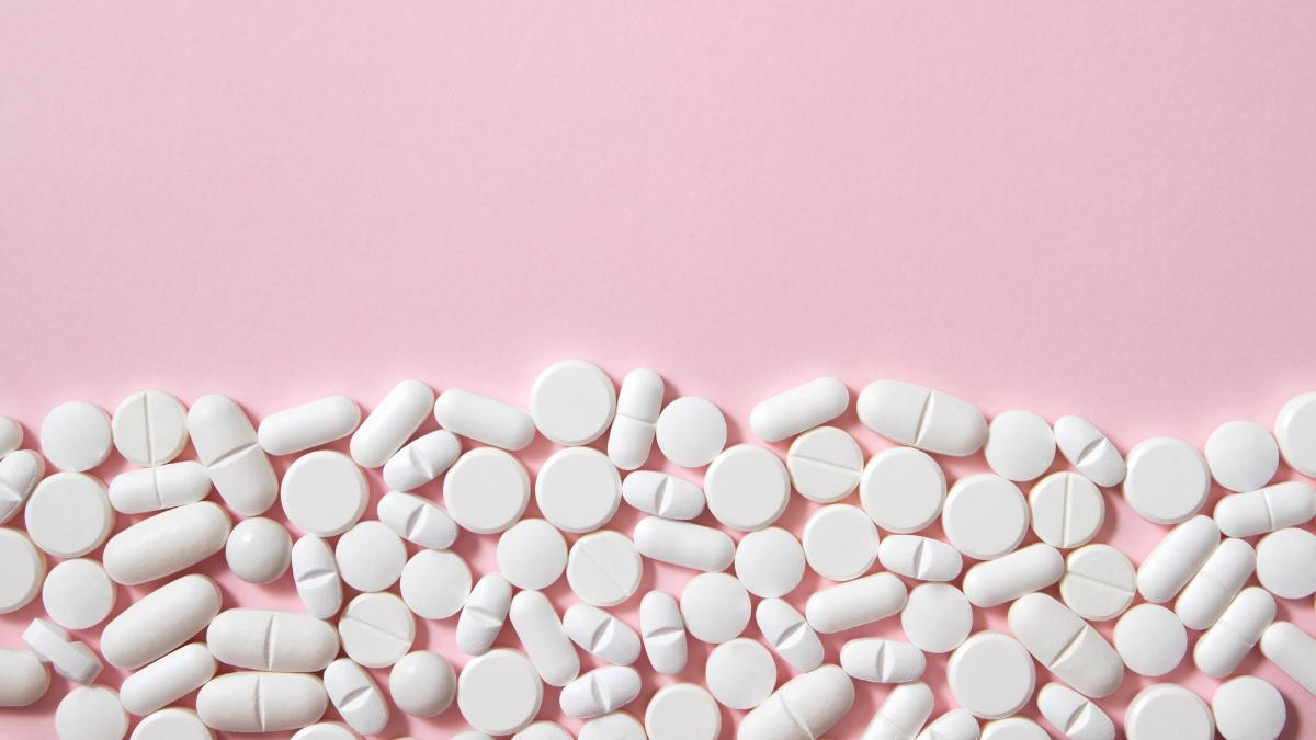 White tablets and pills scattered on a pastel pink background — visual concept for Hims Sex Hard Mints review and modern ED treatments.