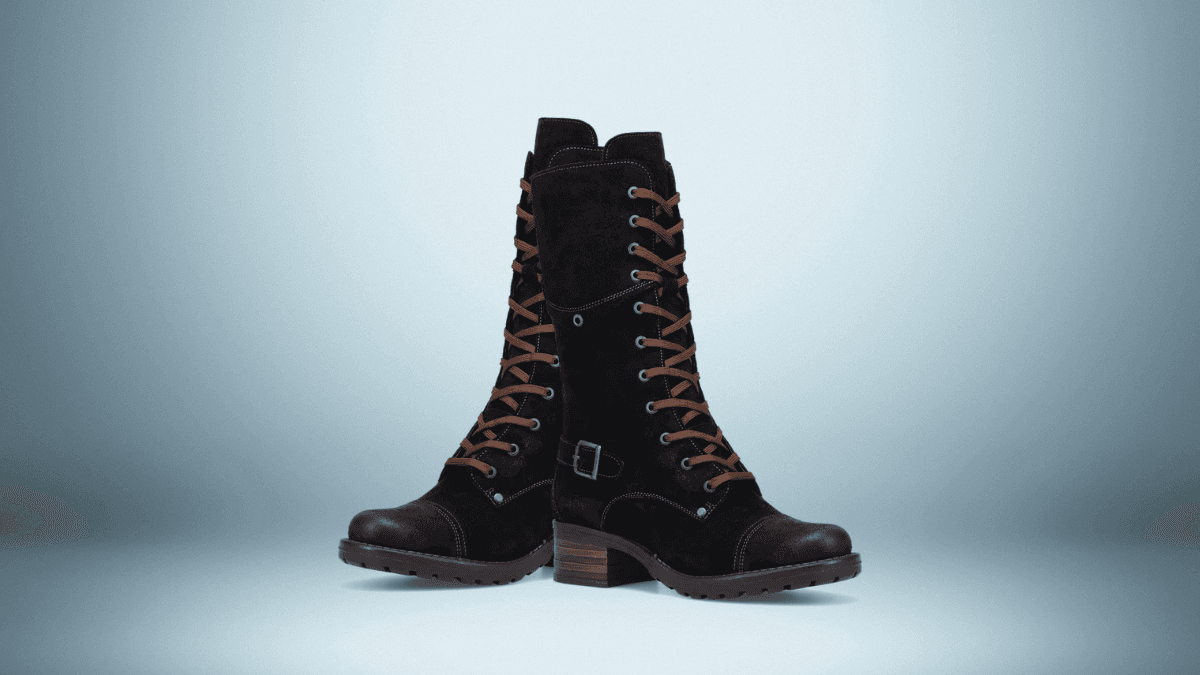 A pair of black suede lace-up boots with contrasting brown laces and a side buckle. These tall boots feature rugged soles and low wooden block heels, offering a stylish and sturdy look, set against a soft gradient blue background.