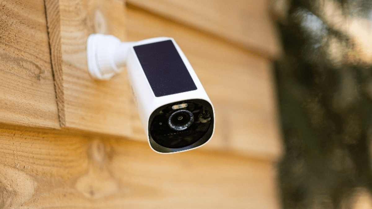 A compact outdoor security camera mounted on a wooden surface, equipped with a solar panel for sustainable power—ideal for remote or eco-friendly monitoring solutions.