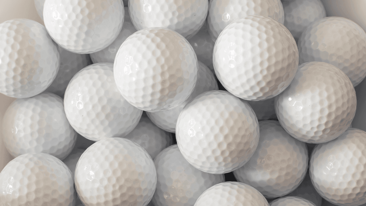 A tightly packed collection of pristine white golf balls, showcasing their dimpled texture and uniform design.