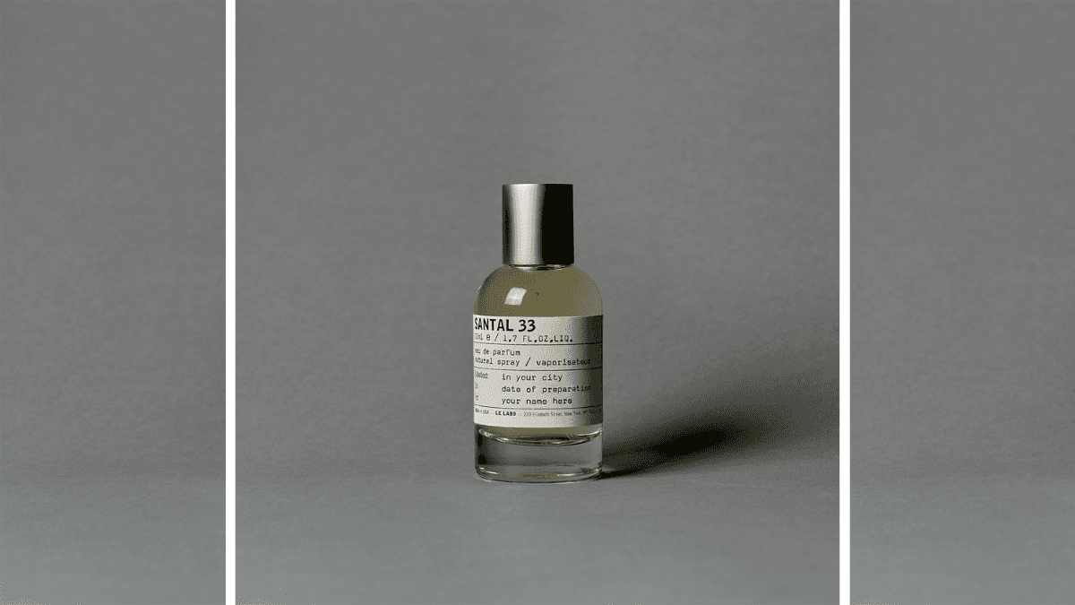 Minimalist product shot of Santal 33 perfume bottle against a neutral gray background, highlighting its sleek design and iconic label.