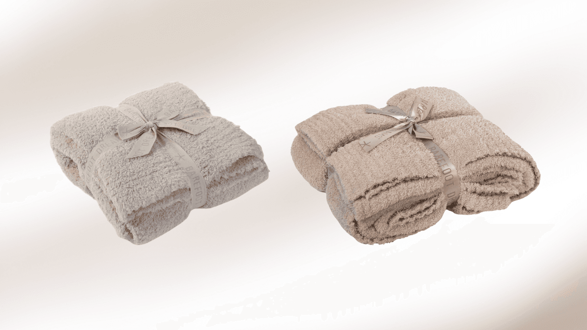 Two plush, neatly folded blankets tied with elegant satin ribbons, displayed on a soft gradient background, highlighting their cozy texture and neutral tones.