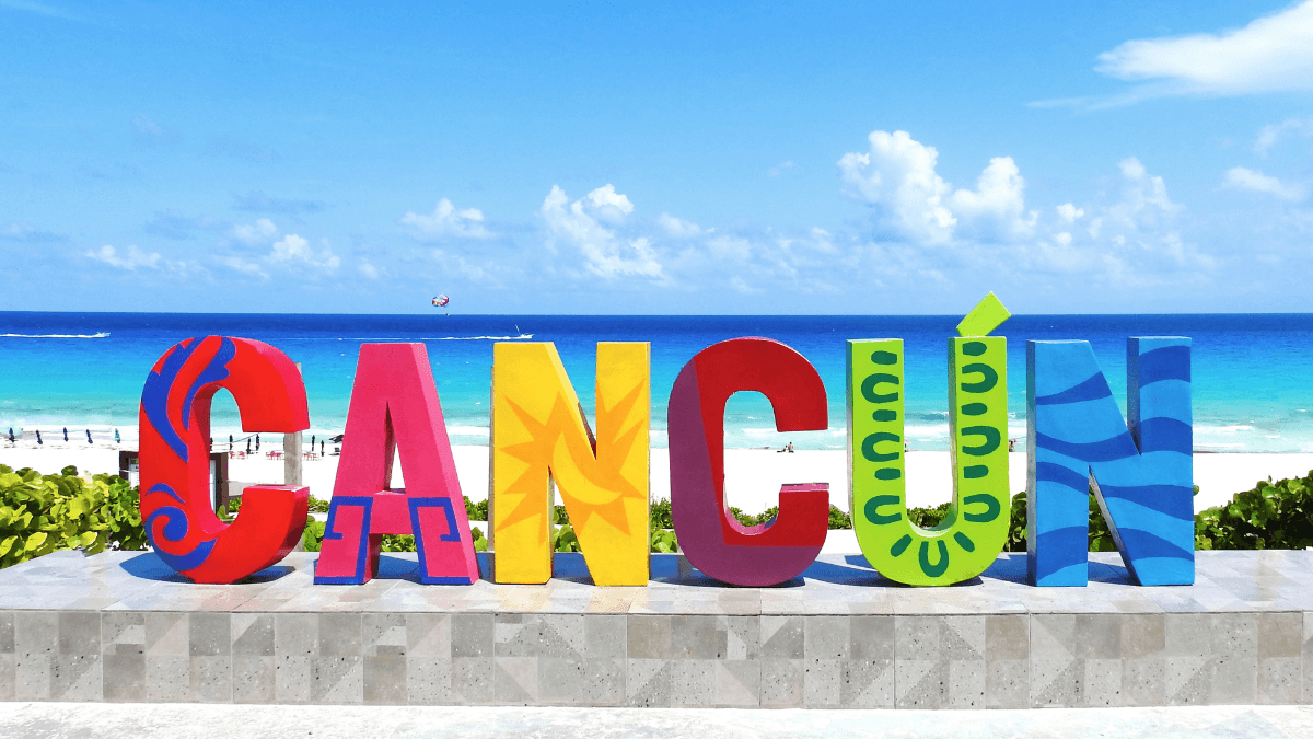 Vibrant Cancún sign with a stunning backdrop of turquoise ocean and blue skies, embodying the tropical paradise vibe.