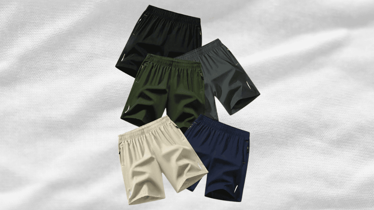 A collection of five athletic shorts in different colors: black, gray, green, beige, and navy blue, displayed on a textured white background.