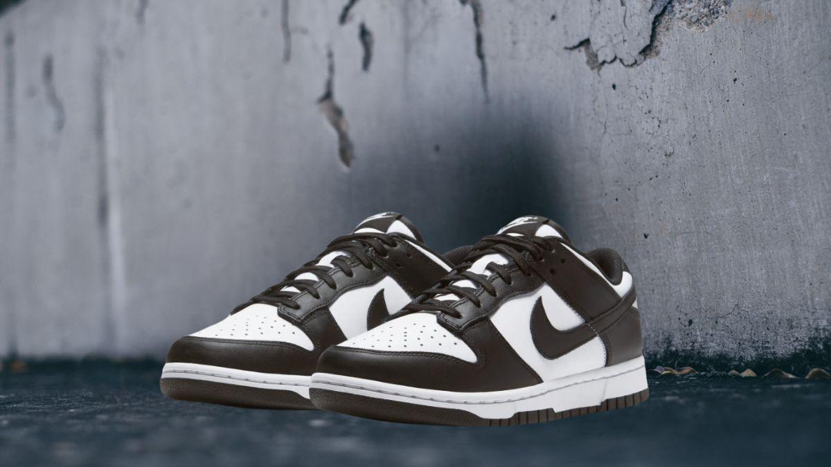 A pair of black and white sneakers placed against a rough, textured wall.