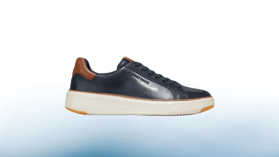 A navy blue leather sneaker with a brown heel accent and a white sole against a gradient background, showcasing a stylish casual design.