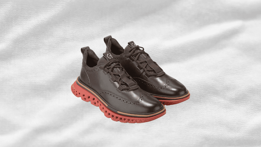 A pair of brown leather wingtip sneakers with a modern red cushioned sole, combining classic brogue detailing with sporty comfort for a stylish, versatile look.
