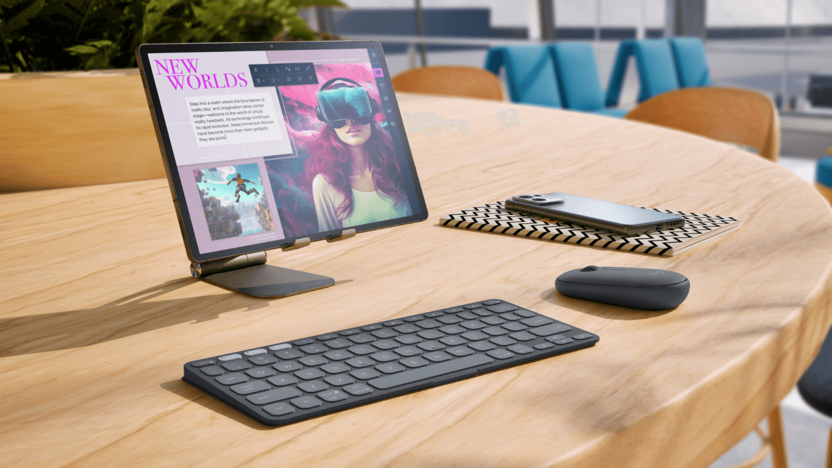 A tablet with a detachable keyboard and mouse on a minimalist desk, with a phone and greenery in the background.