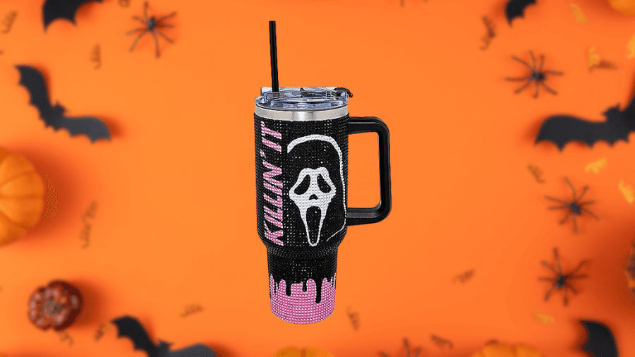 Tumbler with a handle and straw, featuring a design of the Ghostface mask from Scream and the text 'KILLIN' IT,' with black and pink drip details, set against a Halloween-themed background.