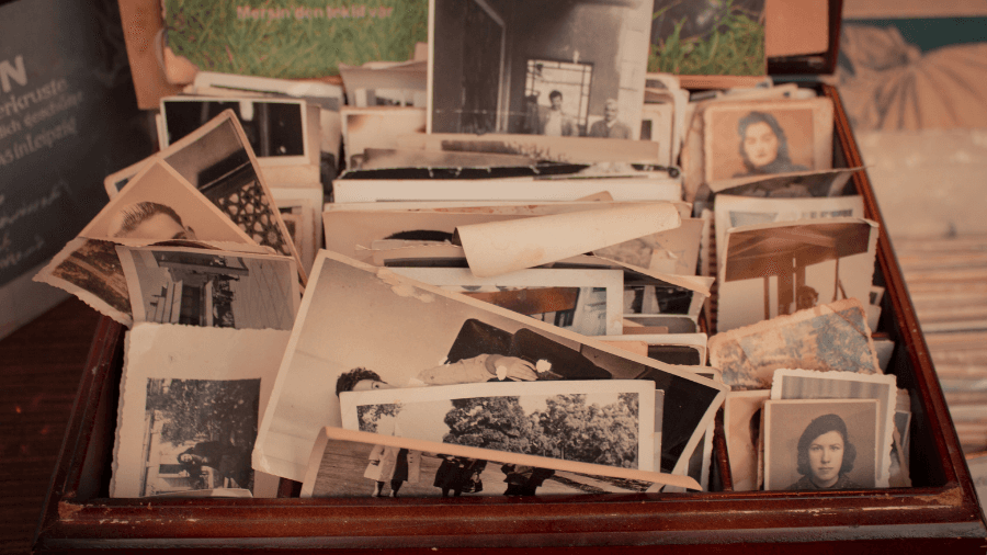 A wooden box filled with old black-and-white and sepia-toned family photographs, showing portraits and candid moments.