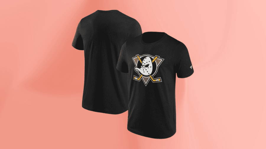 Black Anaheim Ducks t-shirt displayed on a soft pink background. The front features the team's classic Wild Wing logo in black, gold, and white, while the back is plain.