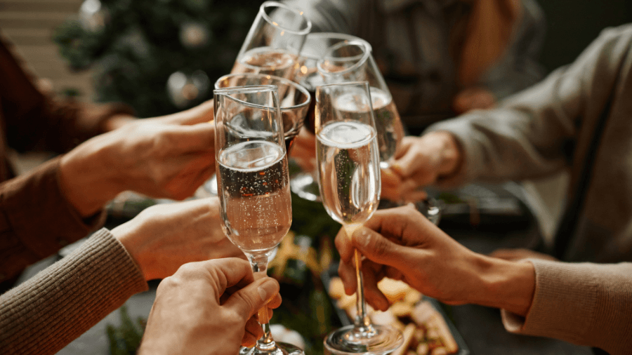A group of people raising champagne glasses in a celebratory toast during a holiday gathering.