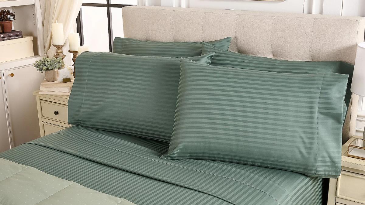Green Northern Nights wrinkle defense dobby stripe sheet set shown neatly arranged on a bed with matching pillowcases.